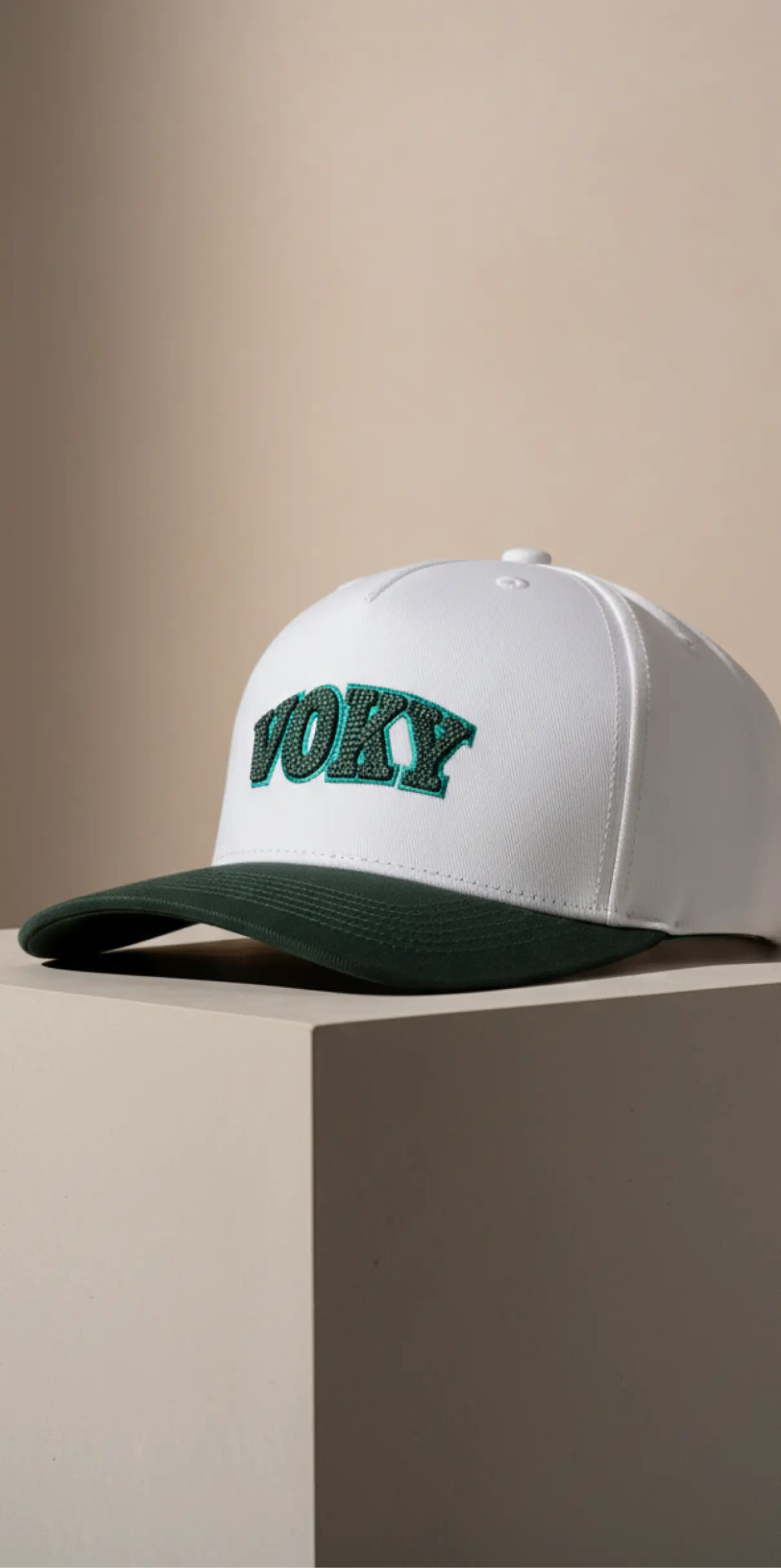 Vit keps med gr&ouml;n sk&auml;rm och "voky" broderat i gr&ouml;nt.